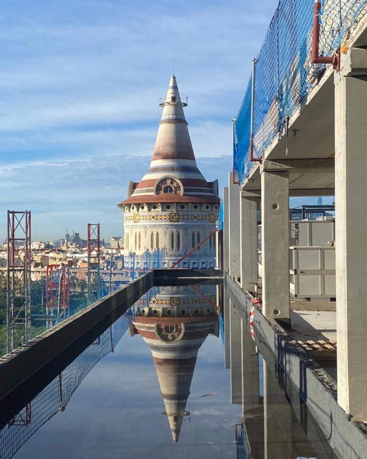 Construction site with a tower reflected in water